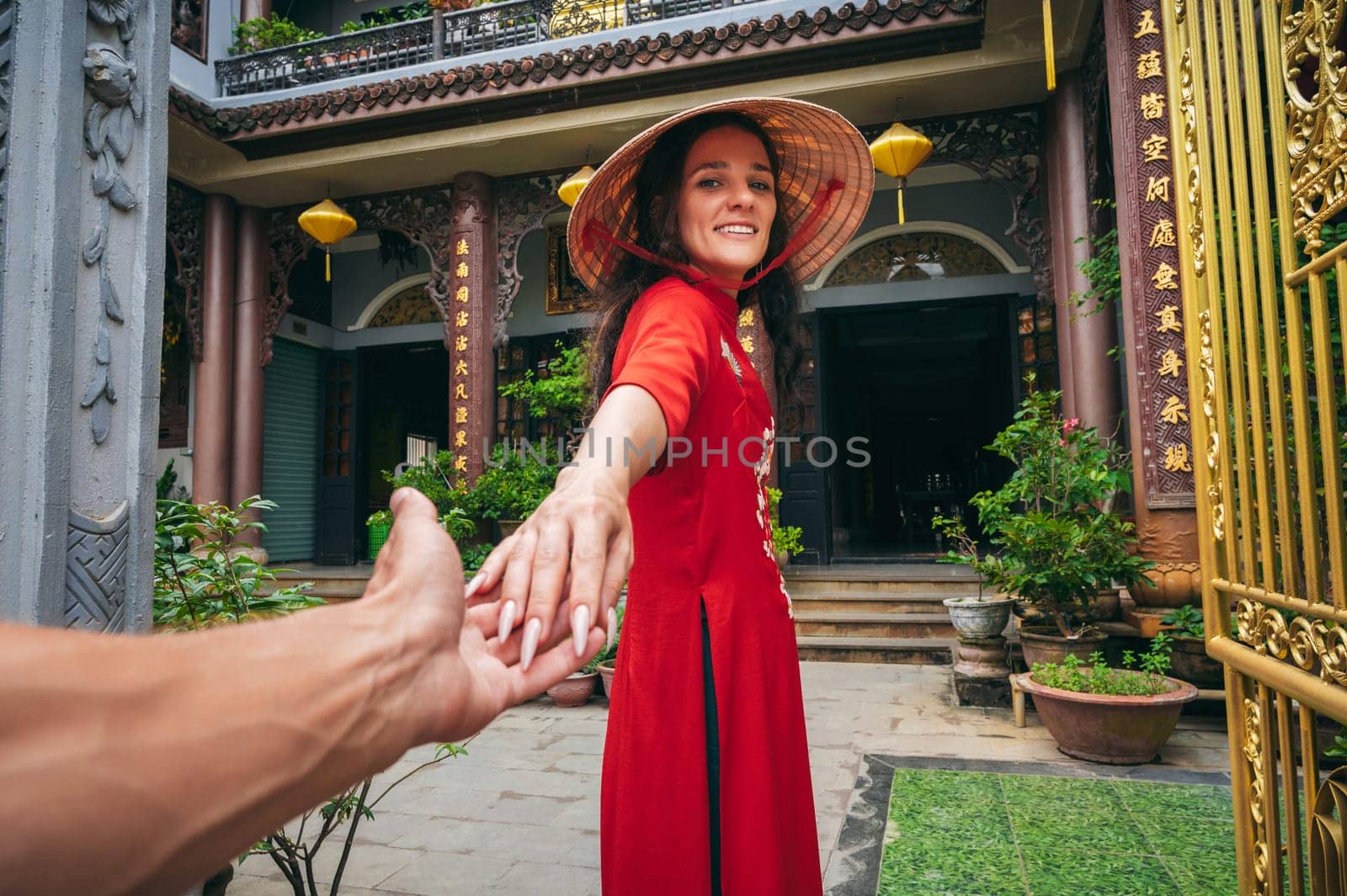 Follow me with a happy female traveler tourist in Vietnamese hat at a temple in Vietnam in Asia. Concept of travel in Asia
