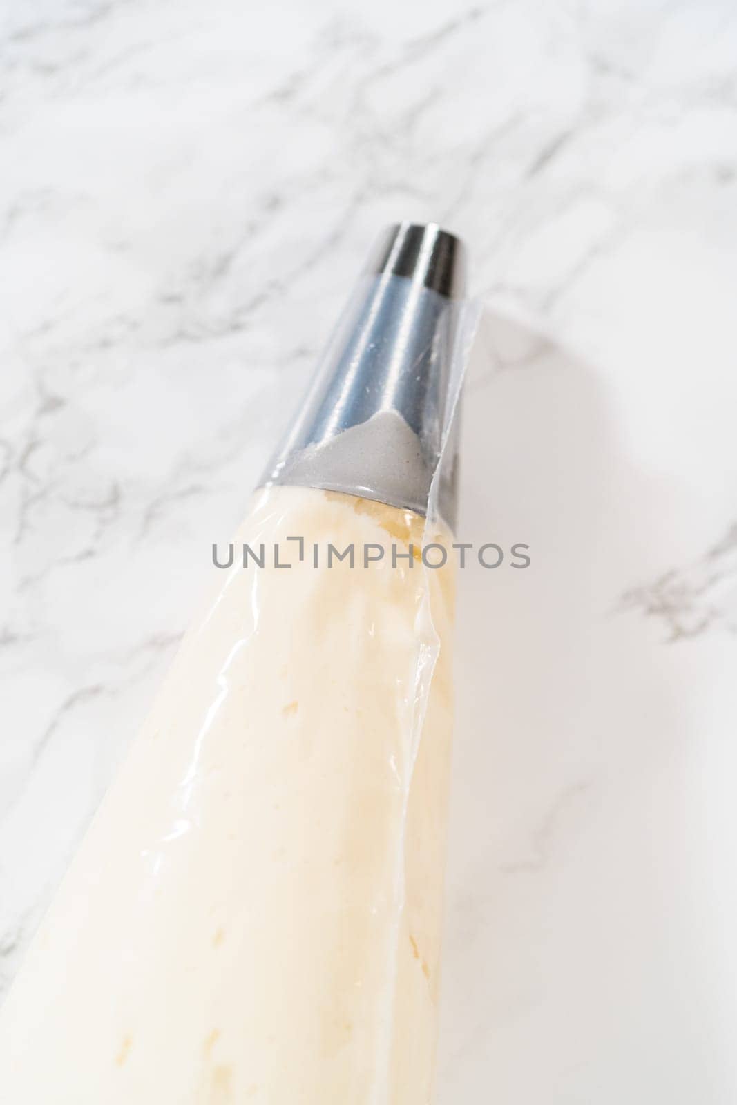 Transferring the homemade cream cheese frosting into a piping bag, ready to create beautiful and delicious decorations.
