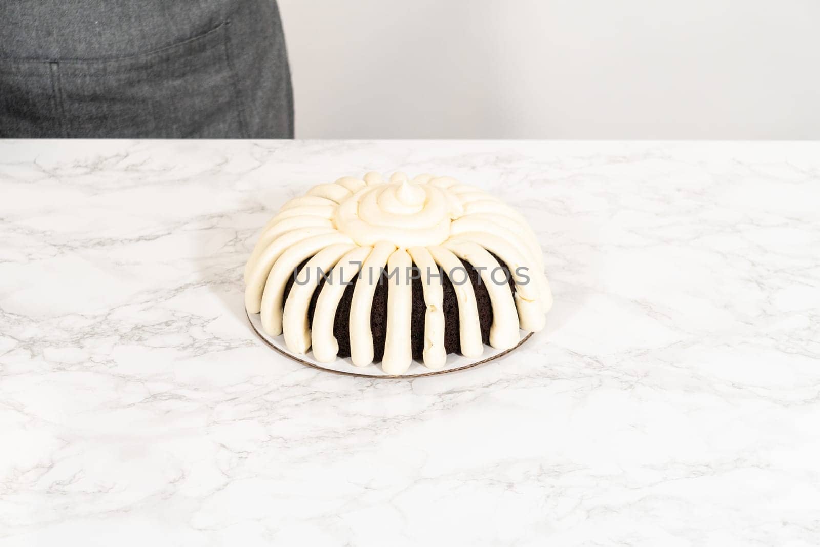 With precision, the Chocolate Bundt Cake is carefully removed from the pan - adorned with luscious cream cheese frosting, creating a delectable treat that is sure to delight.