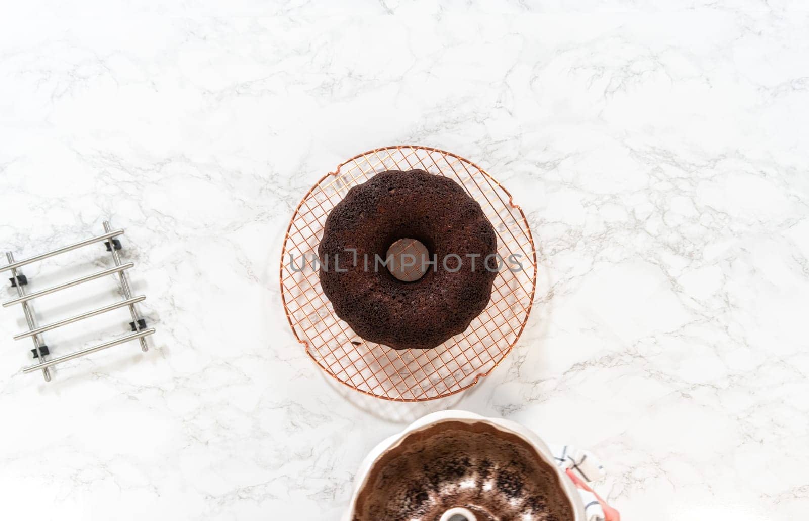 Flat lay. With precision, the Chocolate Bundt Cake is carefully removed from the pan - placed onto a round cooling rack, preparing it for a flawless presentation and delightful indulgence.