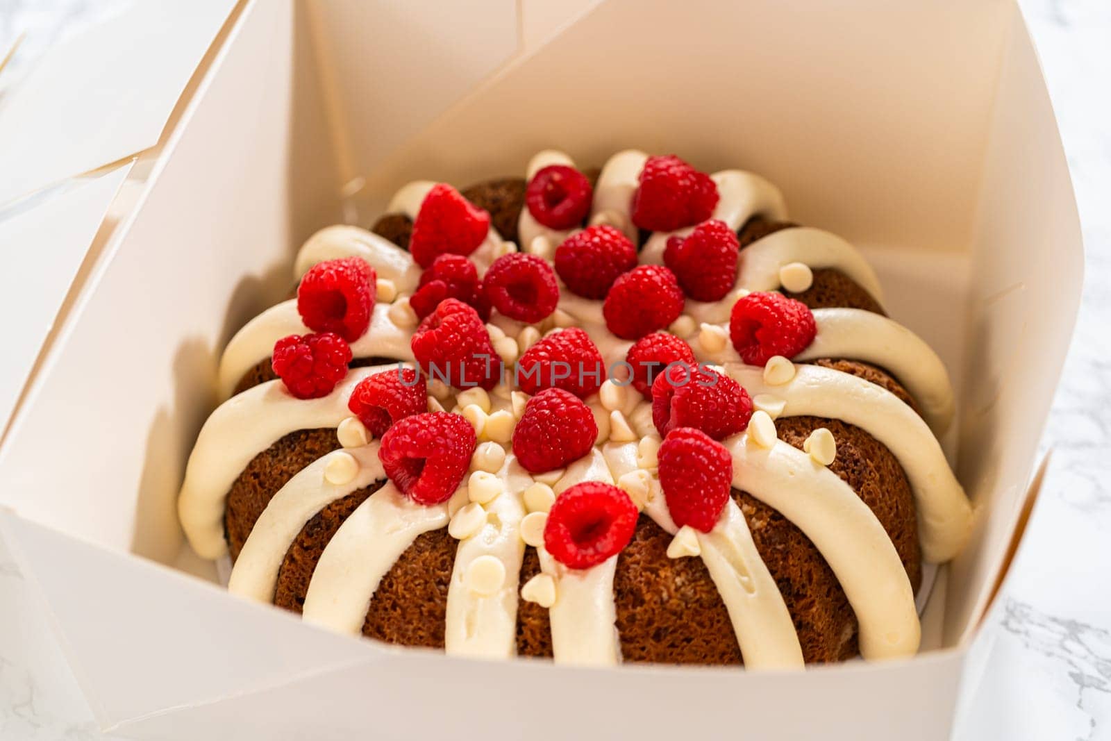 With care, the White Chocolate Raspberry Bundt Cake is packaged into a white paper box - ready for gifting to bring joy and indulgence to someone special.