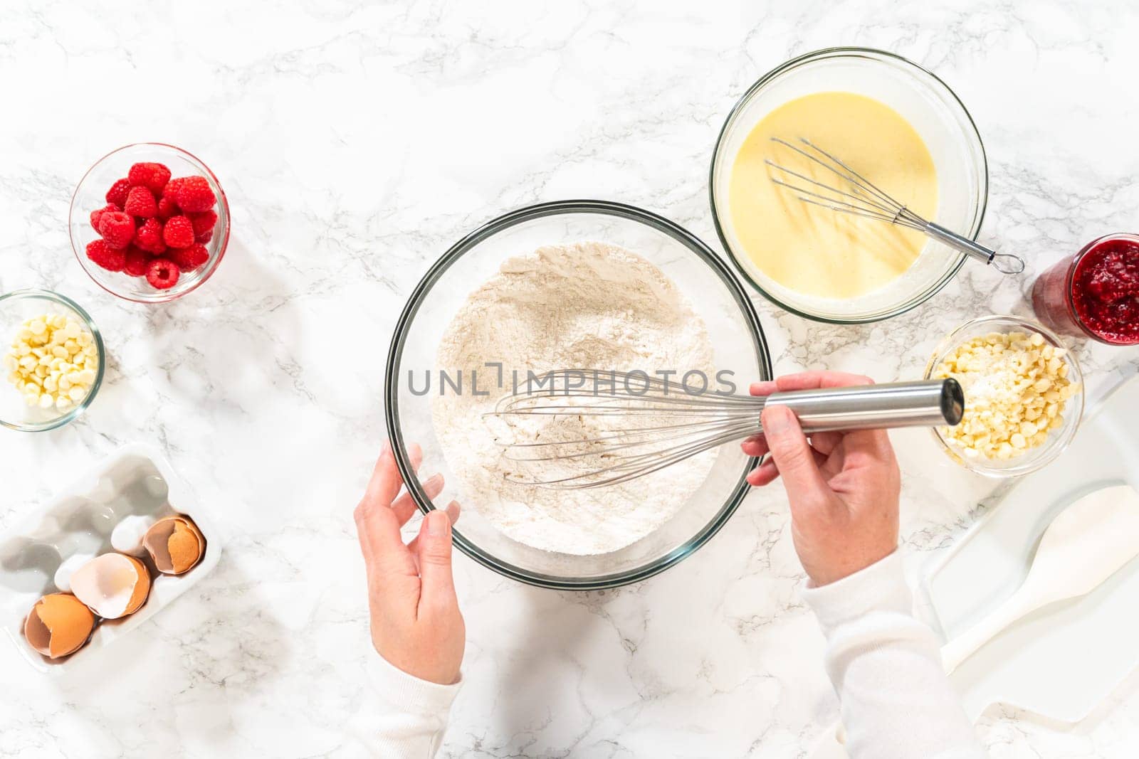 Flat lay. With a hand whisk, the measured ingredients come together - expertly mixed to prepare the cake batter for this delightful bundt cake.