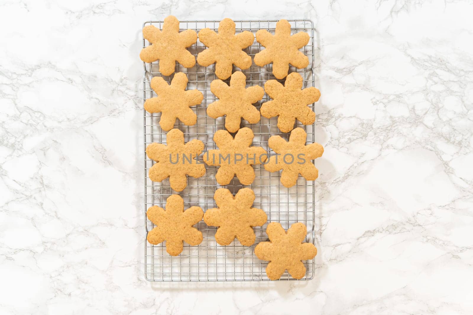 Overhead view of snowflake-shaped amber gingerbread cookies cooling on a wire rack, ready for serving or decoration.