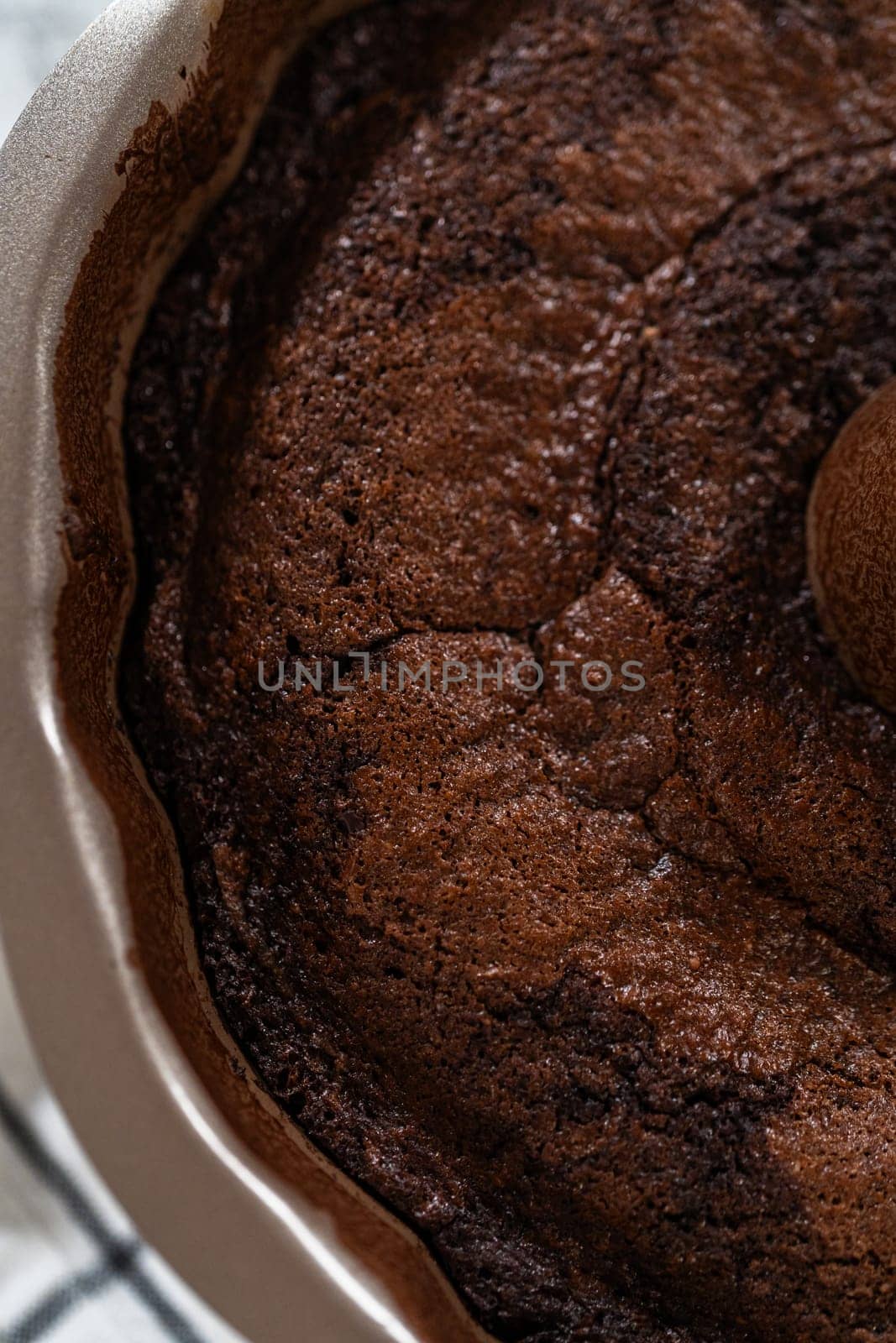 With precision, the Chocolate Bundt Cake is carefully removed from the pan - placed onto a round cooling rack, preparing it for a flawless presentation and delightful indulgence.