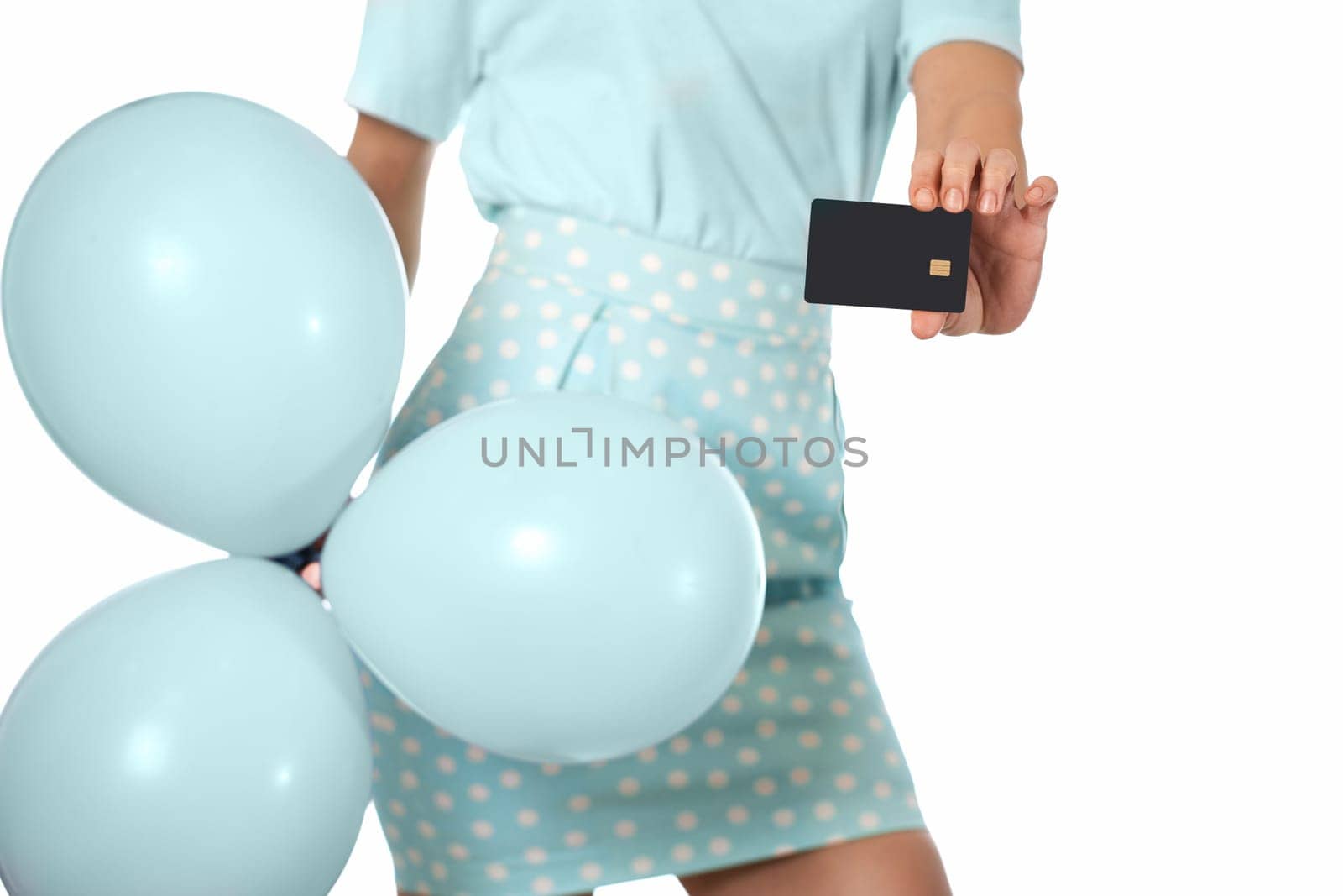Caucasian female hand holding black premium credit bank card and blue festive air balloons on white background. digital business finance