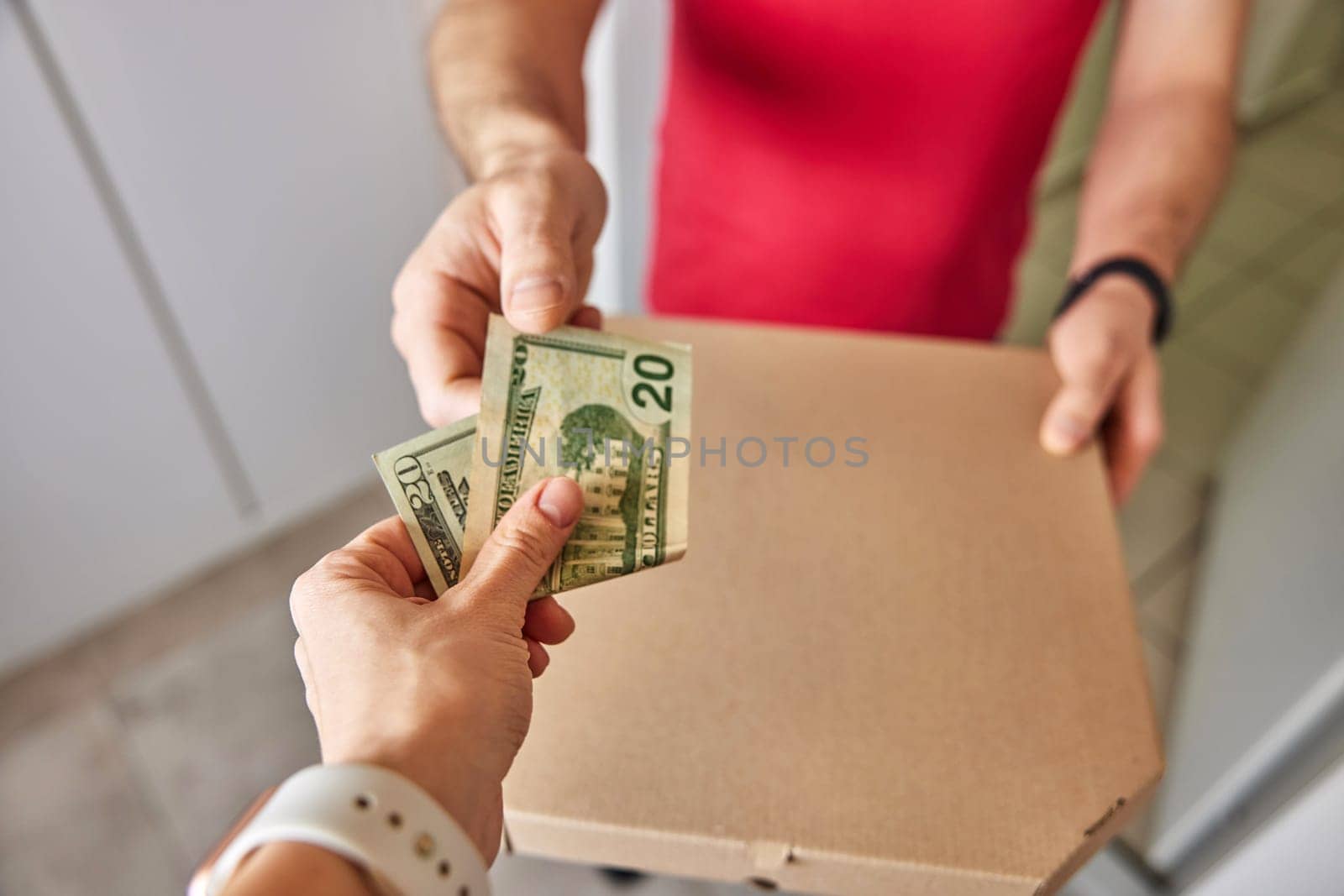 delivery man giving pizza in paper boxes to customer and taking payment at home