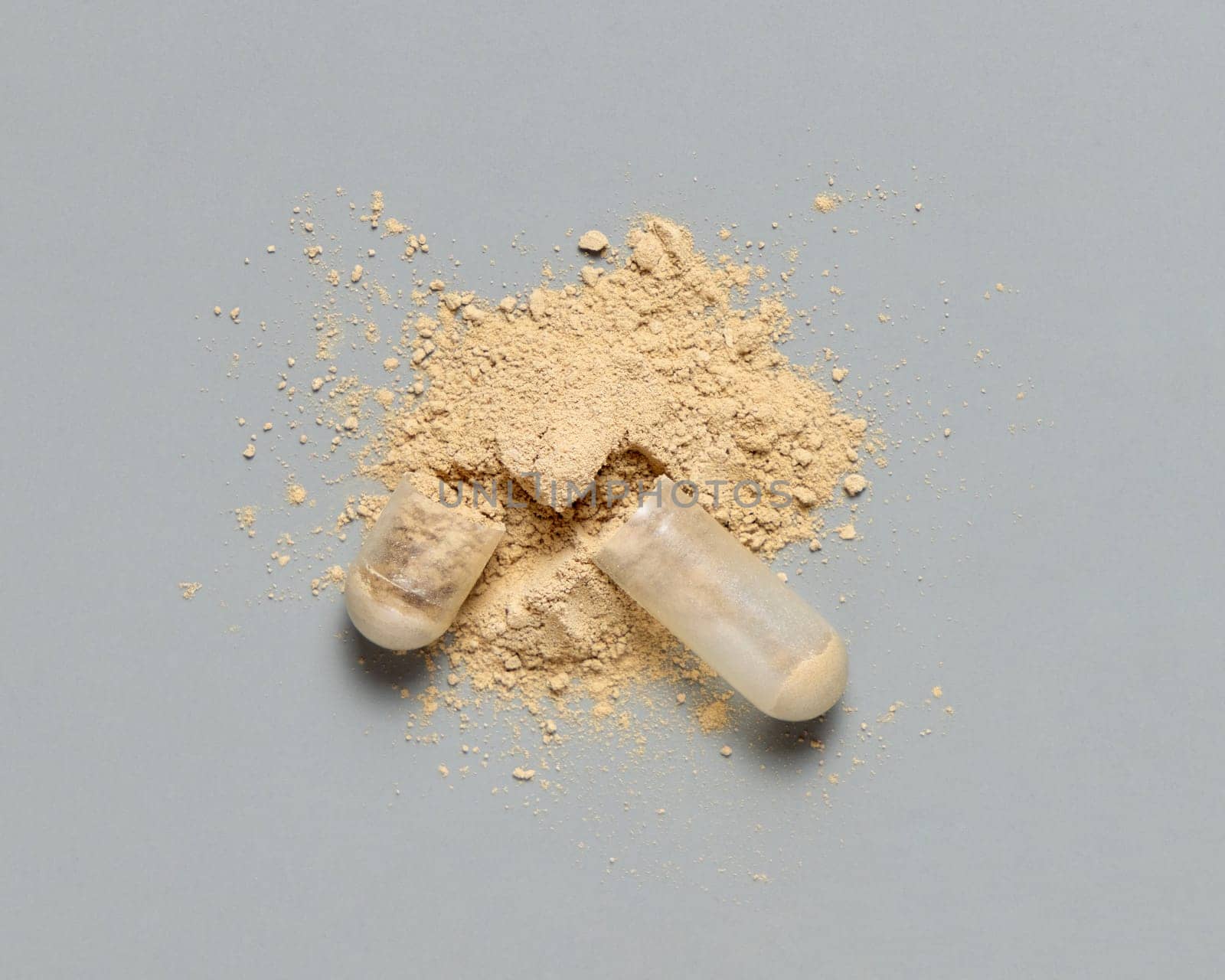 Opened medical capsule to show beige powder on grey top view. Preventive medicine and healthcare, taking alternative dietary supplements and vitamins