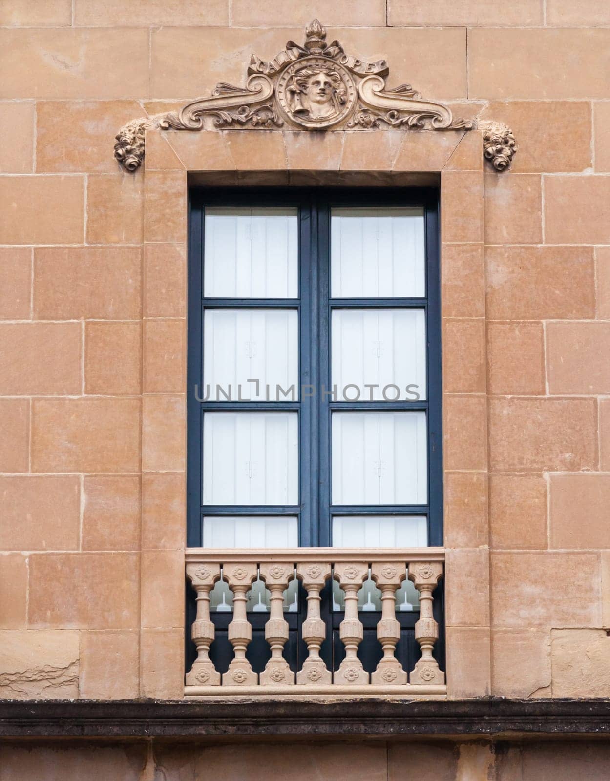 A beautifully crafted window with ornate columns and decorative motifs showcases classic architecture in a city building.
