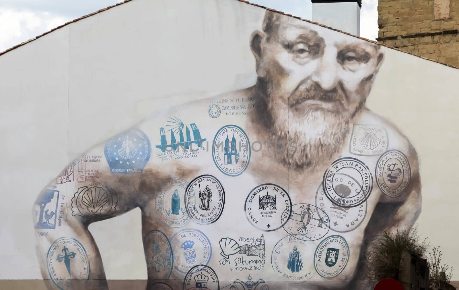 Logrono, SPAIN - May 25, 2016 - A detailed mural showcases a man adorned with various stamps representing the Camino de Santiago, emphasizing the essence of pilgrimage.