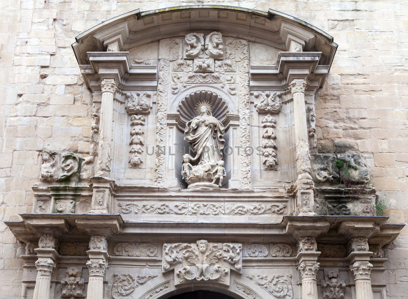A beautifully detailed stone relief depicting a religious figure, framed by ornate architecture, captures attention.