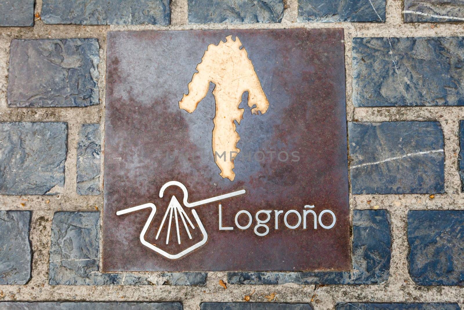 A brass plaque indicates the Camino de Santiago path in Logrono, guiding pilgrims on their journey.