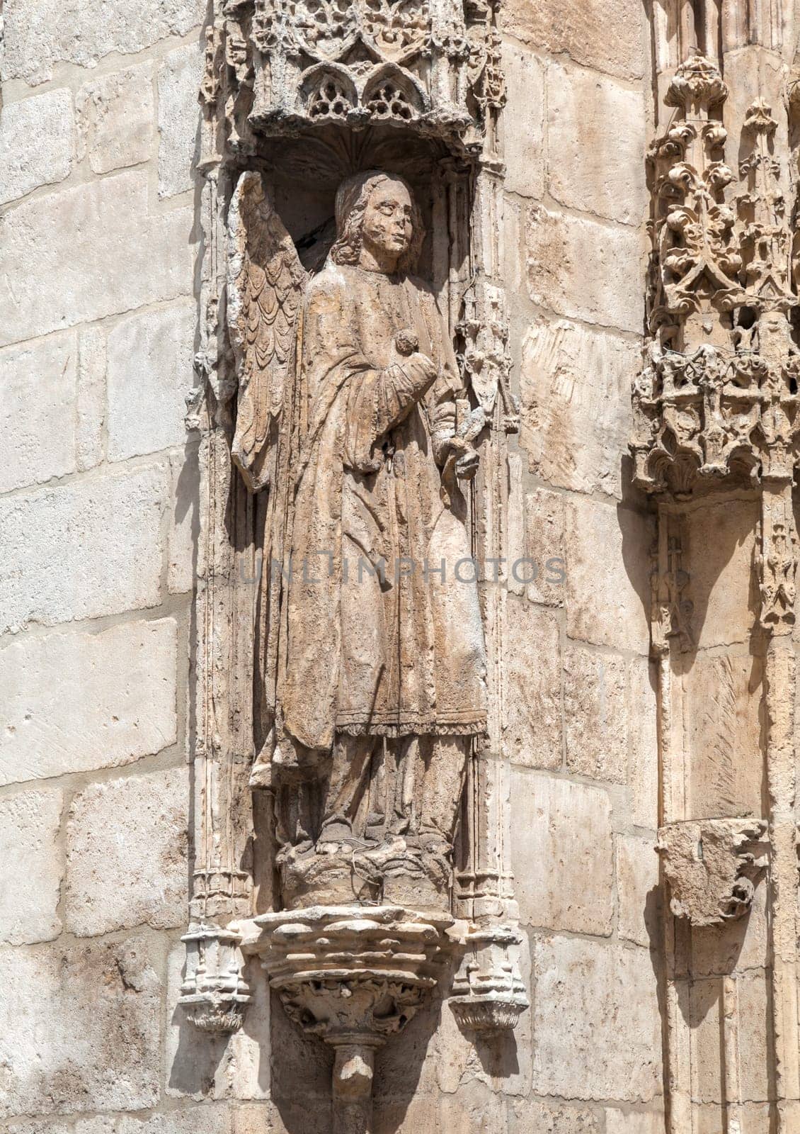 Intricate stone sculptures of religious figures enhance the architecture of the Burgos Cathedral, showcasing artistry.