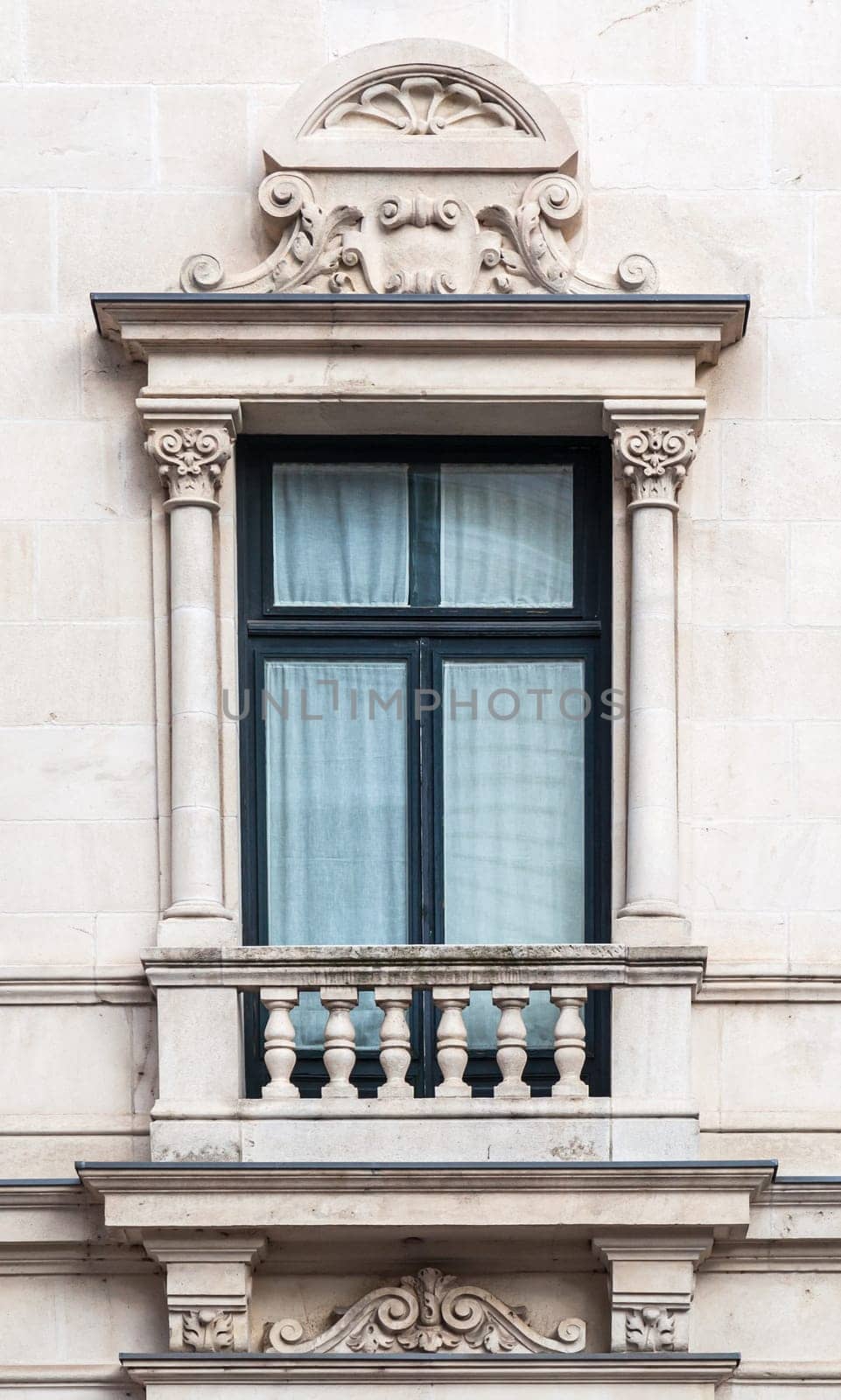 A beautifully crafted window with ornate columns and decorative motifs showcases classic architecture in a city building.
