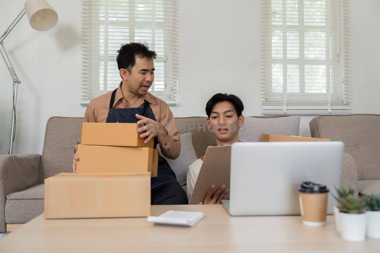 Two online sellers engage in teamwork at home, preparing packages and collaborating on their business.