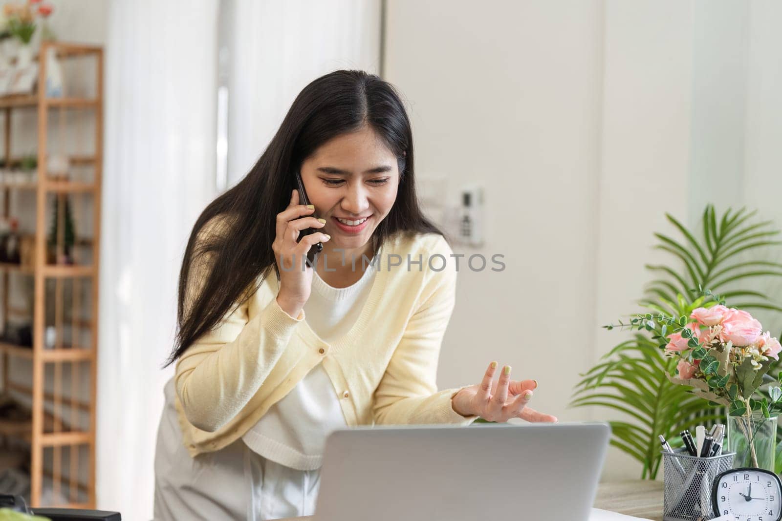 A happy businesswoman talks on the phone in her home office, showcasing a productive work environment.
