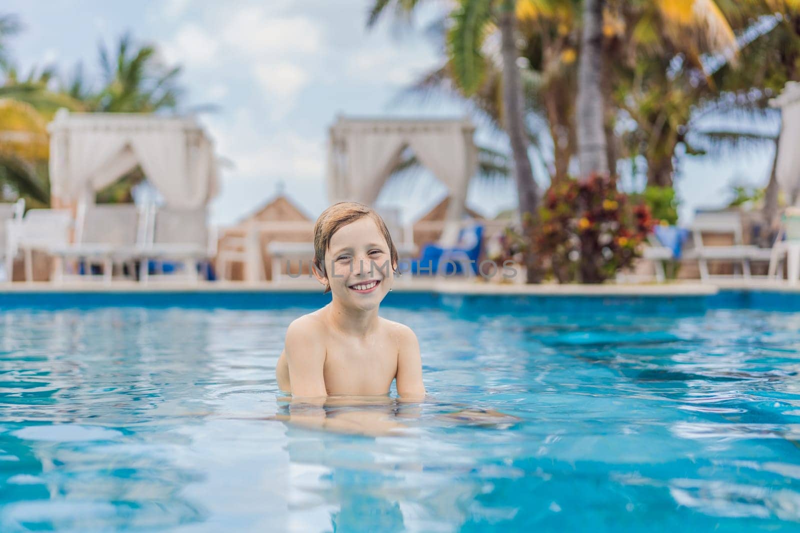 A young boy joyfully swims in a tropical pool surrounded by lush greenery. The vibrant scene captures the essence of summer fun, adventure, and carefree childhood moments in a refreshing outdoor setting.