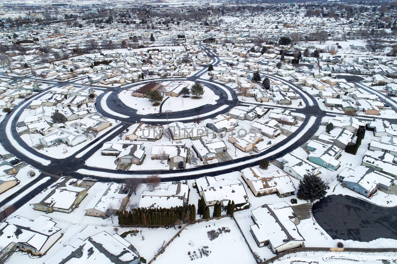 A snowy town with houses and a round street. The houses are all white and the street is also covered in snow