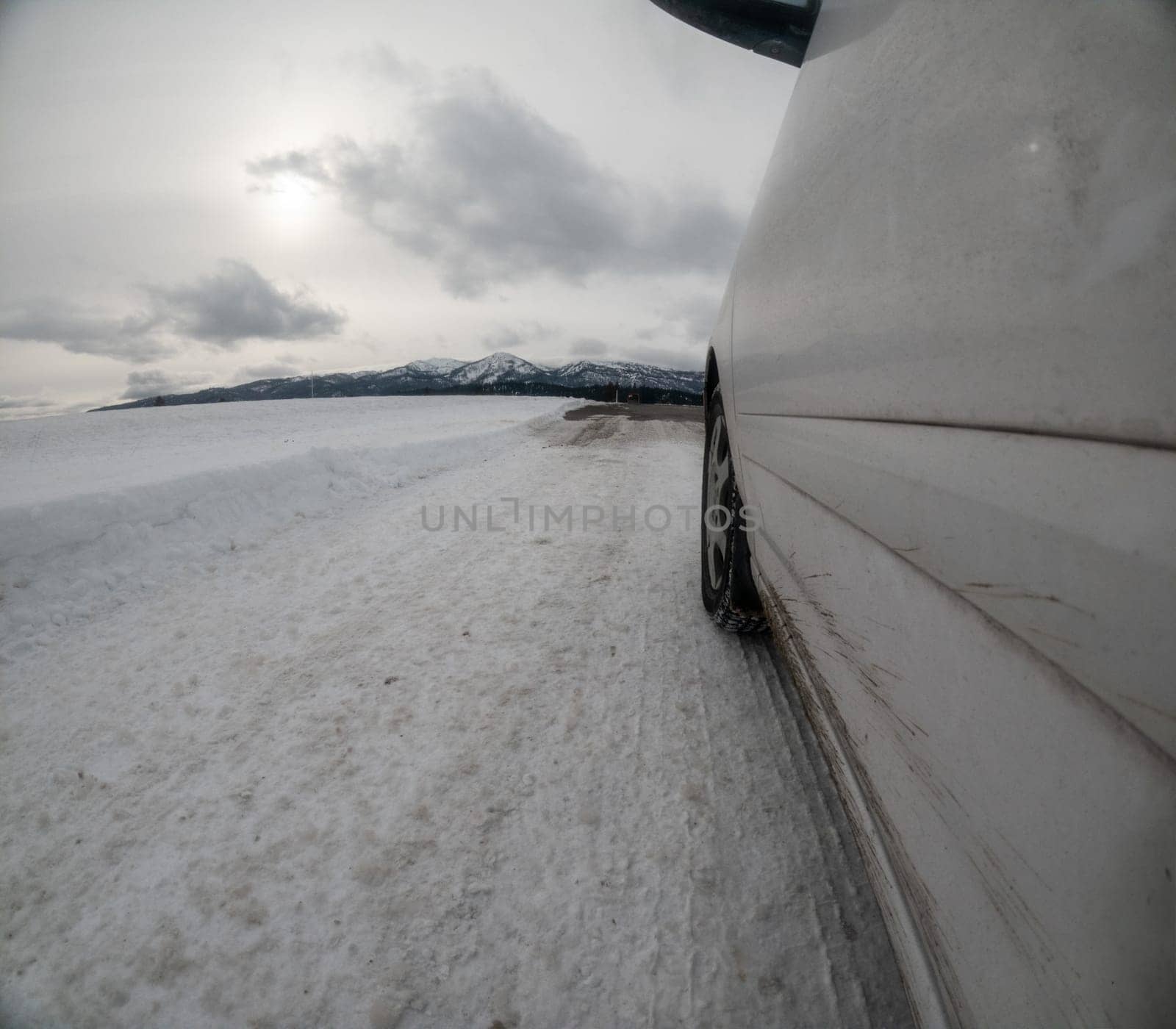 Car traveling down a slick road that is covered in snow