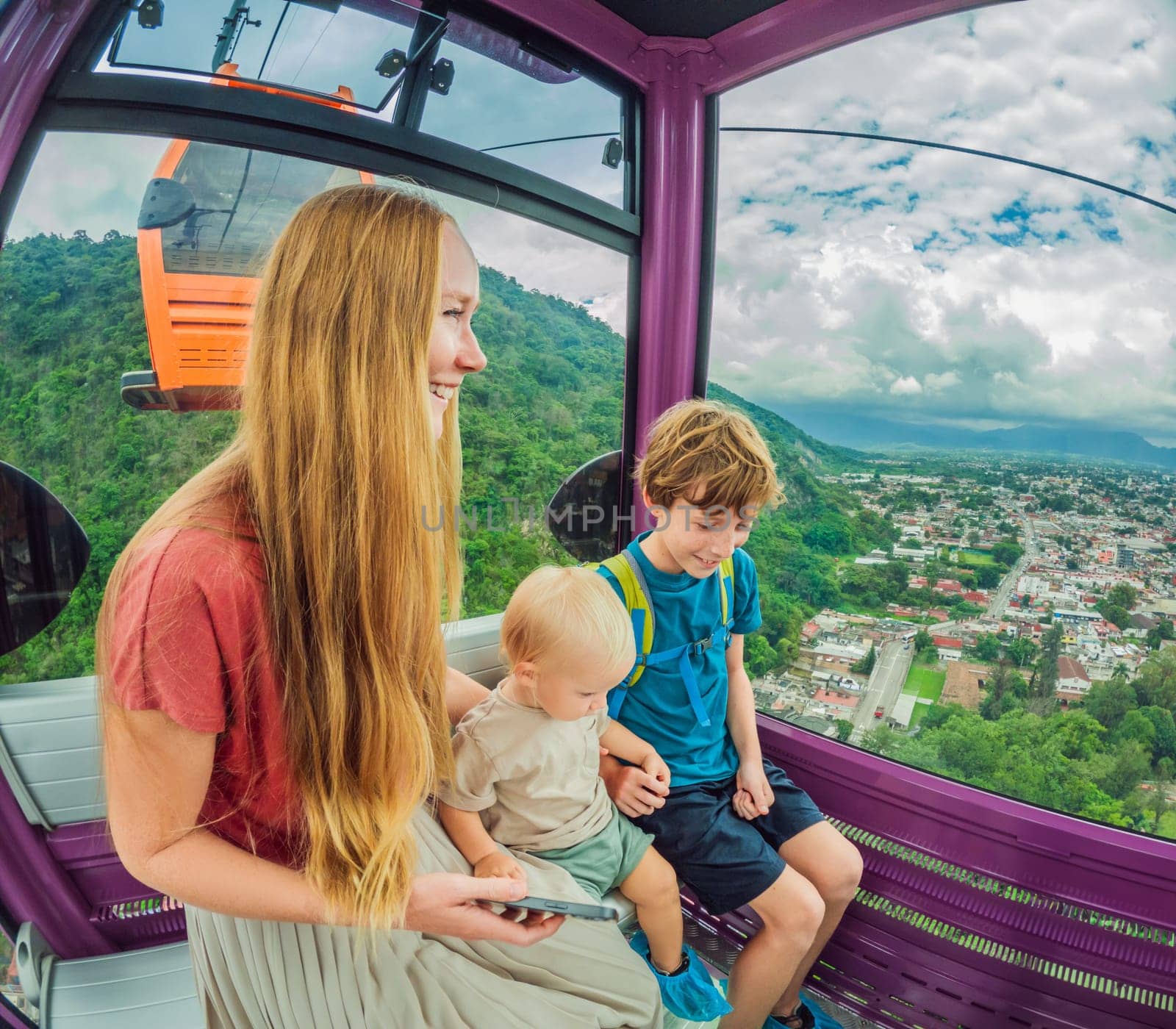 Mother and two sons on a cable car ride in Orizaba, Mexico. Scenic family adventure with panoramic views of the city, lush mountains, and iconic landscapes. Concept of family bonding, travel, and exploration in nature.