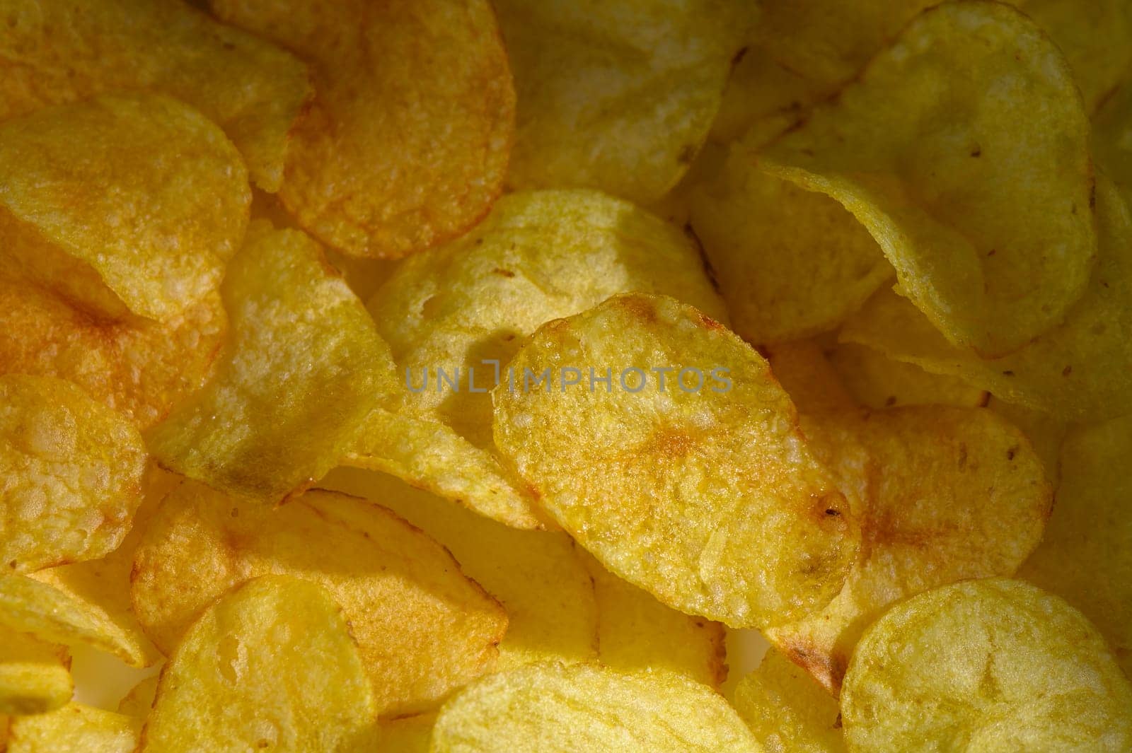 A vibrant collection of golden potato chips rests together, offering a tempting crunch for snack enthusiasts.