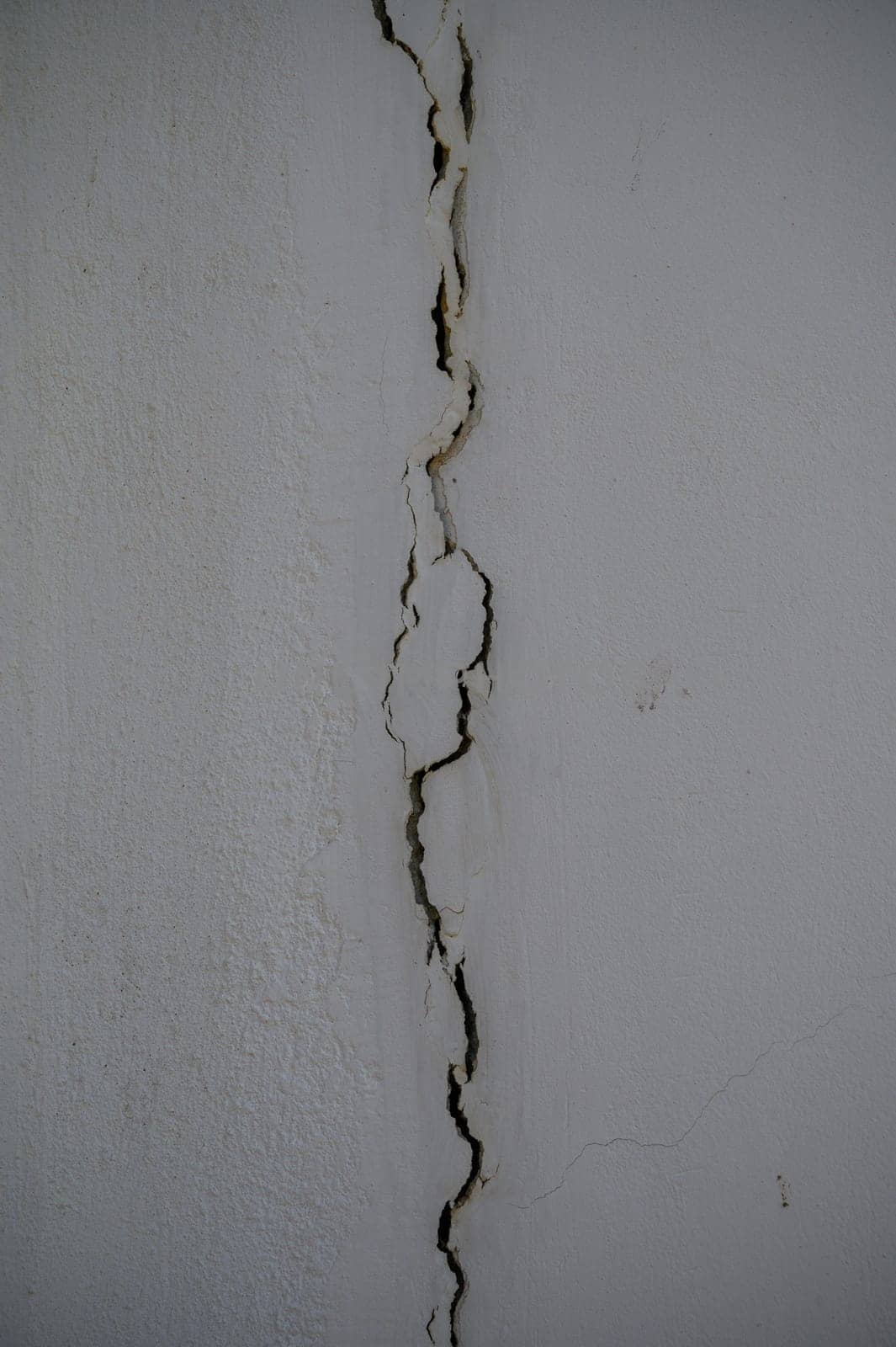 Deep fissures snake through the plaster, showcasing the weathered character of this neglected interior space.