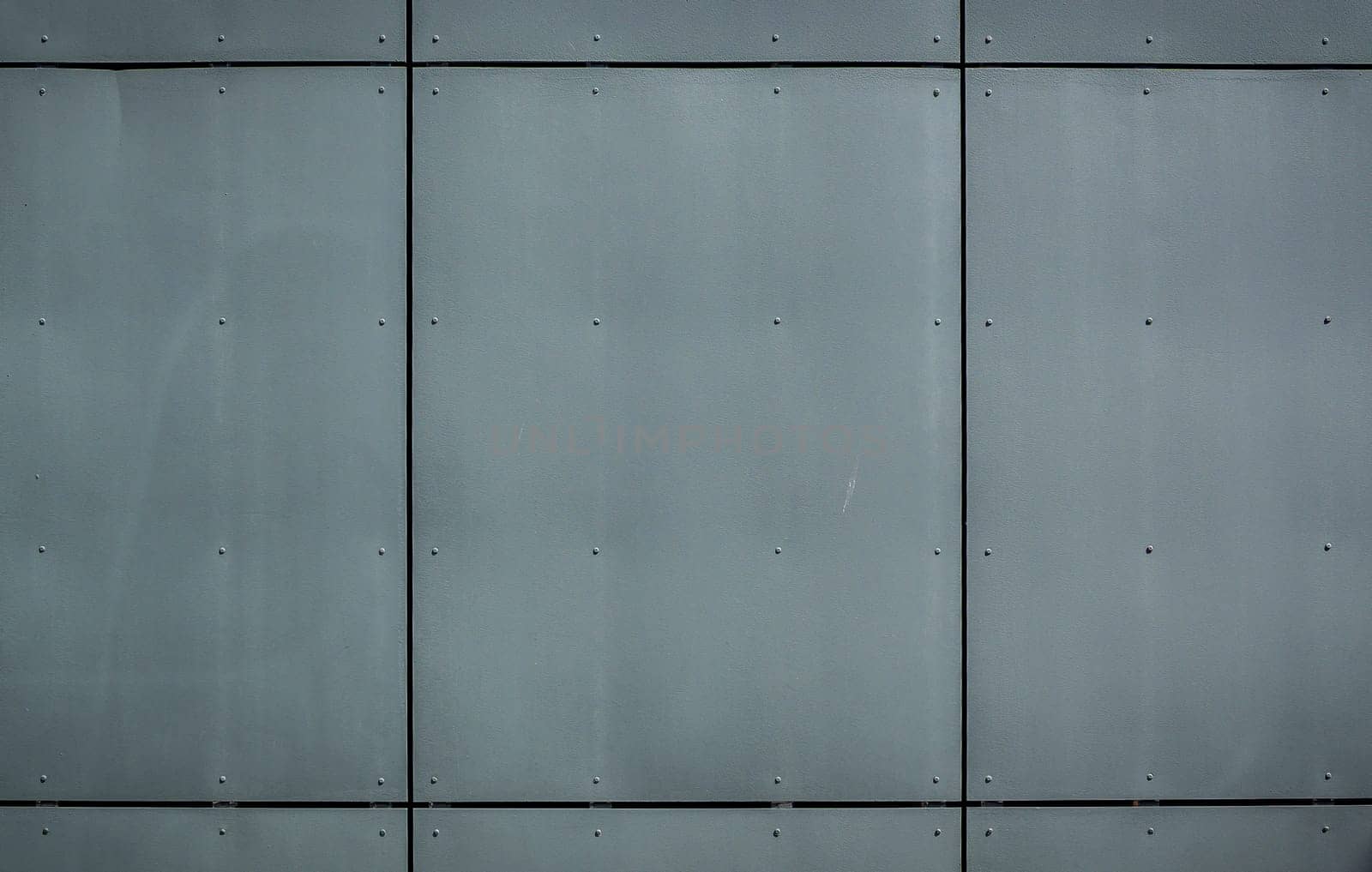 A smooth, industrial wall features large metal panels reflecting a contemporary design, showcasing urban elegance.