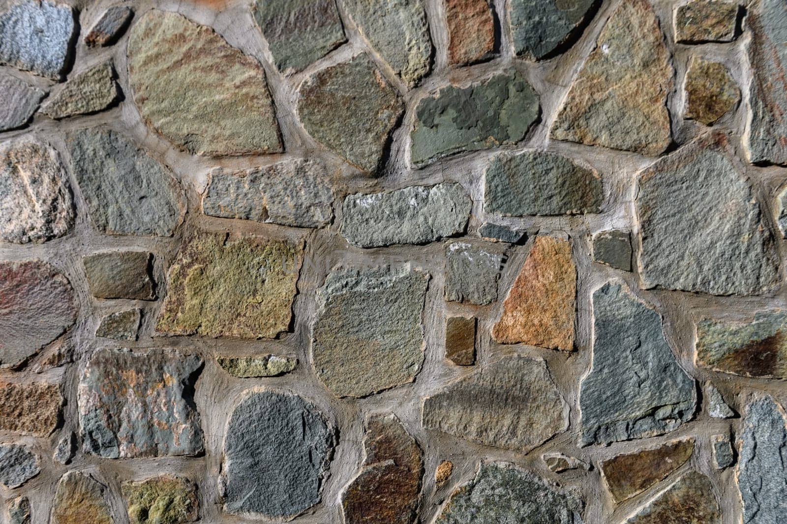 Richly textured stone wall features a mosaic of earthy colors and irregular shapes, showcasing timeless craftsmanship.