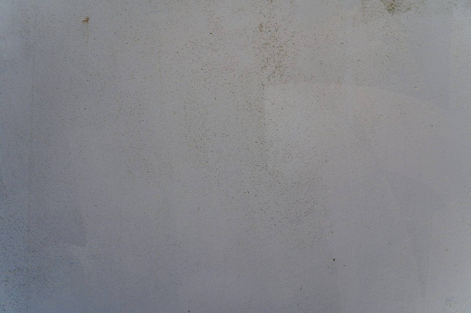 A textured wall displays a blend of muted colors and imperfections, capturing a serene, quiet atmosphere in daylight.
