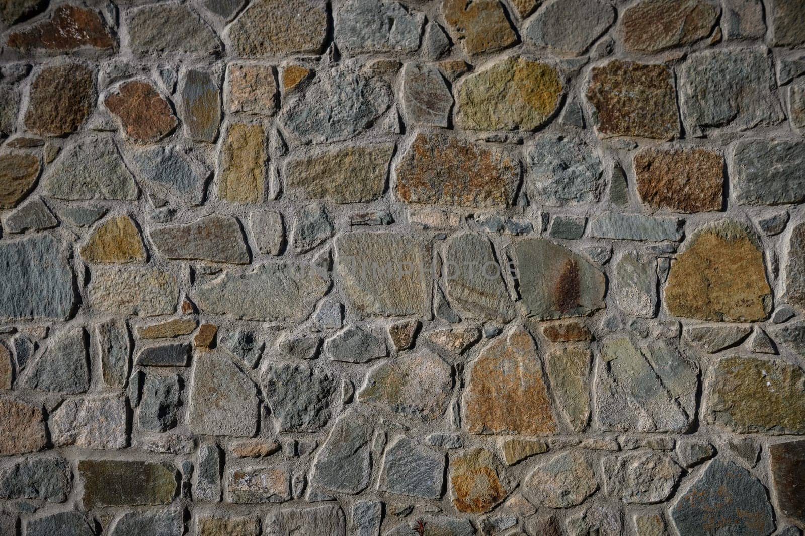 Natural stones blend in earthy tones create a rustic wall, showcasing textures and patterns unique to each stone.