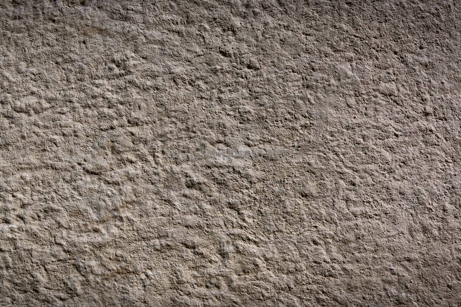 Rough and uneven wall with a muted tone highlights the beauty of simplicity and natural wear over time.