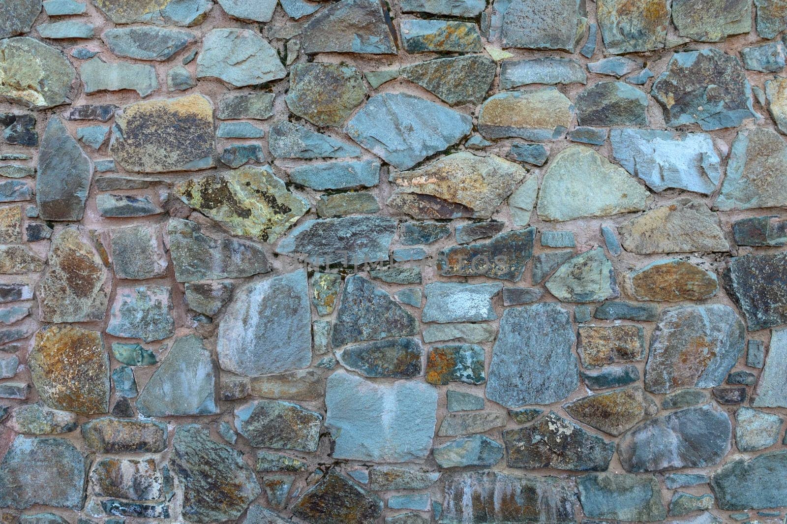A patterned stone wall displays a mix of colors and textures, highlighting craftsmanship and natural beauty.