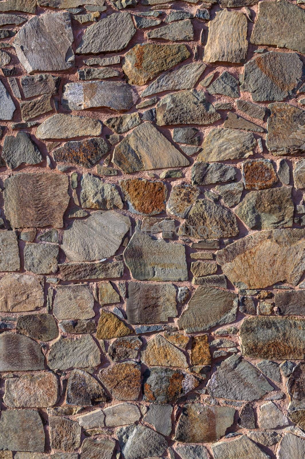 A beautifully crafted stone wall displays a variety of textures and earthy colors, creating a warm, inviting atmosphere.