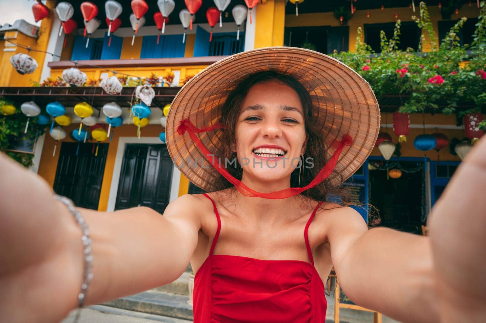 selfie of happy woman tourist in traditional Vietnamese hat on the street in old town in Hoi An city in Vietnam in Asia