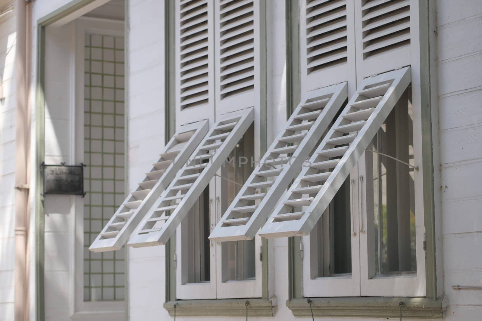 Two wooden shutters are open wide, showcasing the warm sunlight.