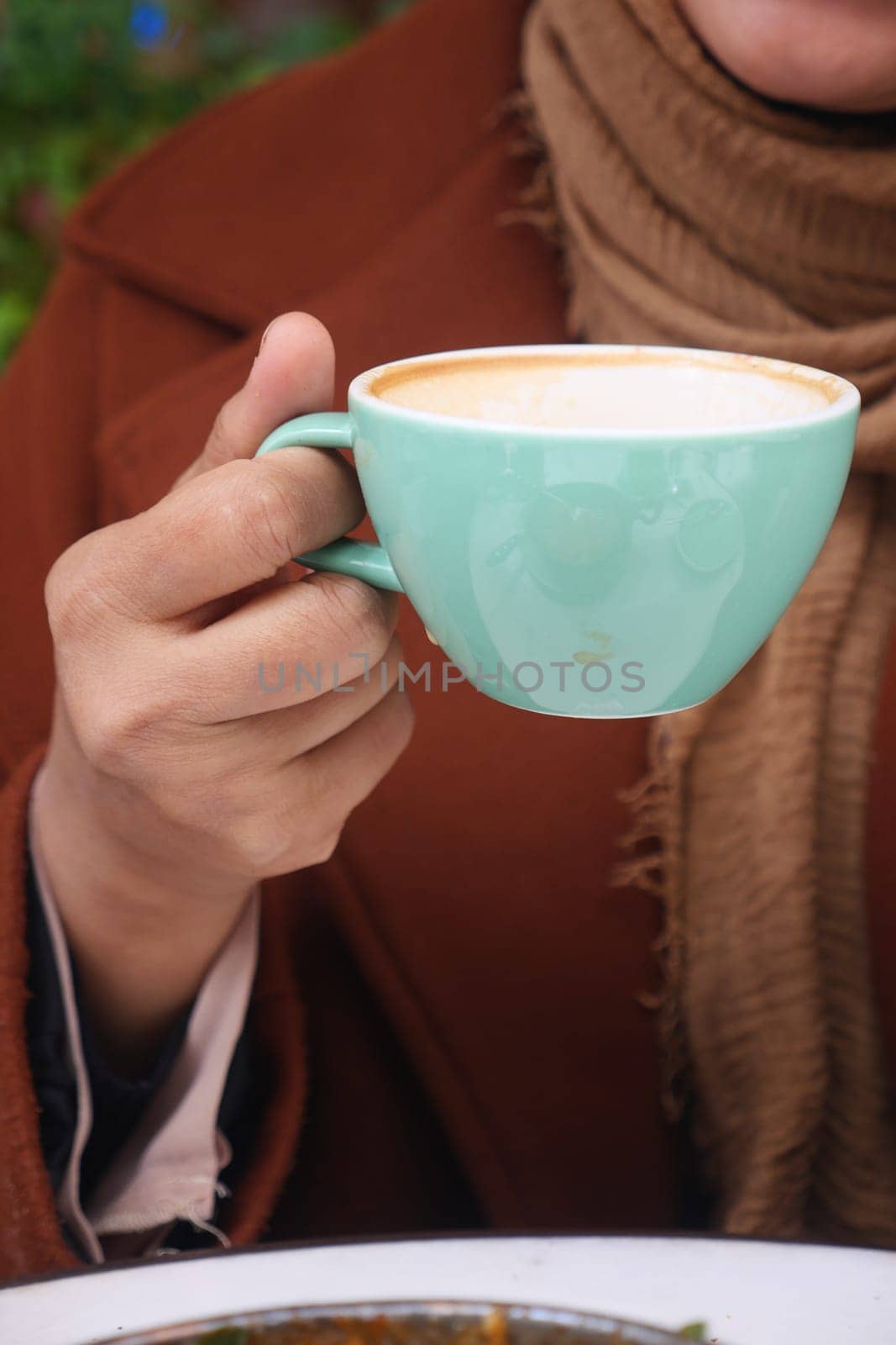 A person enjoys a warm cup of coffee on a cool day outdoors.
