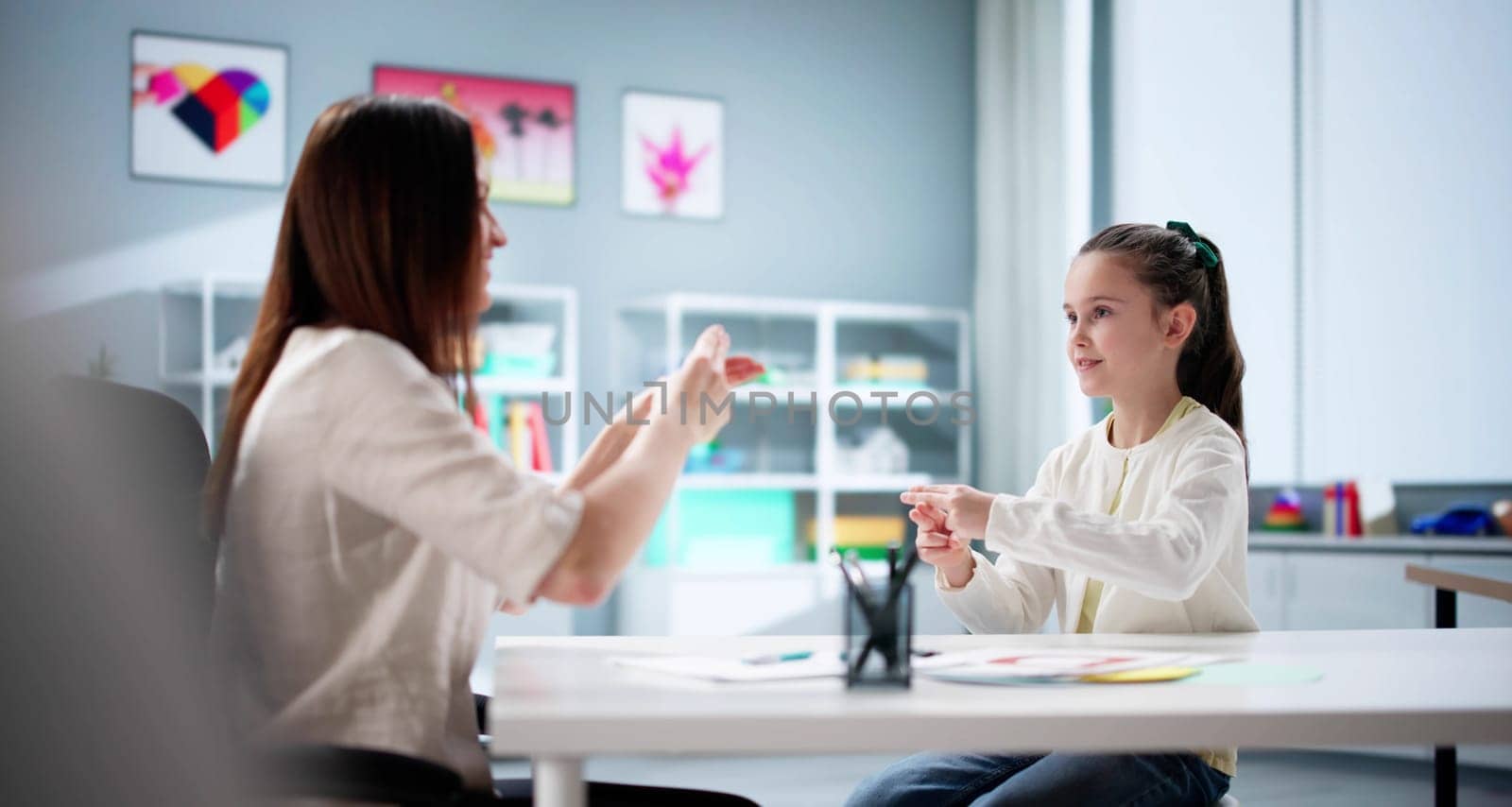 Little girl learns sign language from hearing disability teacher. Healthcare profession.