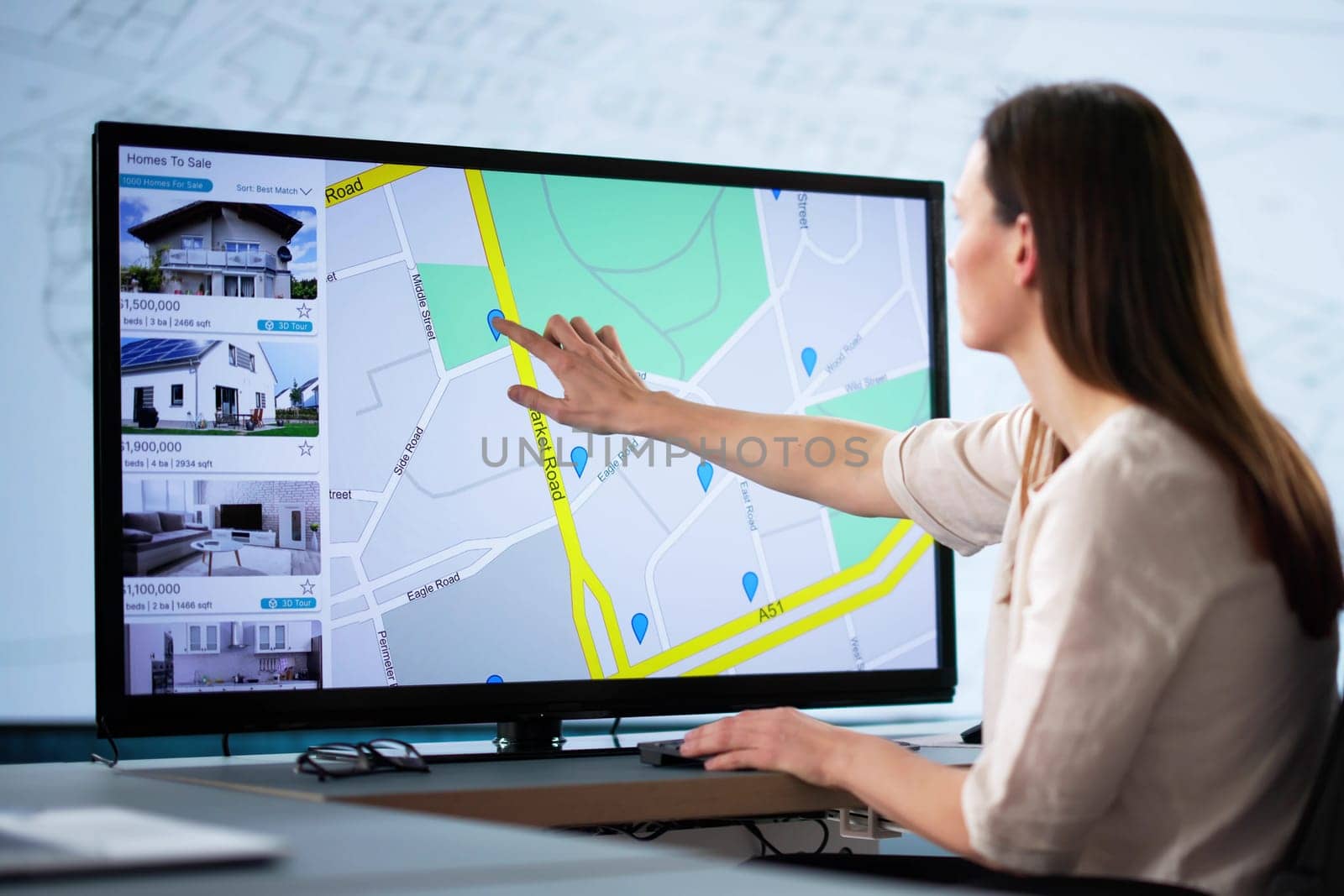Young female caucasian using computer to search online real estate.