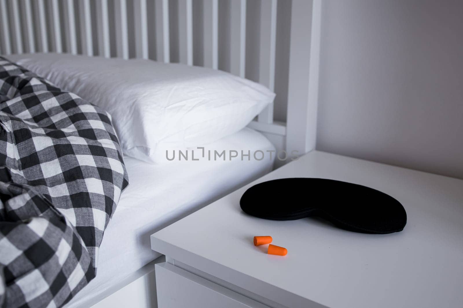 Cozy bedroom with sleep mask, earplugs, and checkered bedding for a restful night.
