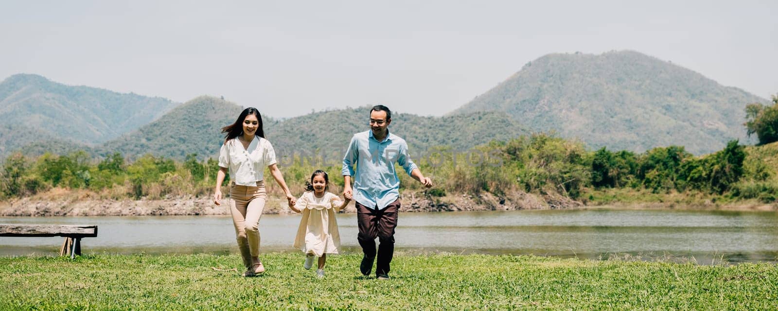 Asian family father mother and daughter holding hands and running lake in park, lifestyle parents and child kid enjoying outdoors together in nature on summer travel, Family relaxation, Front view