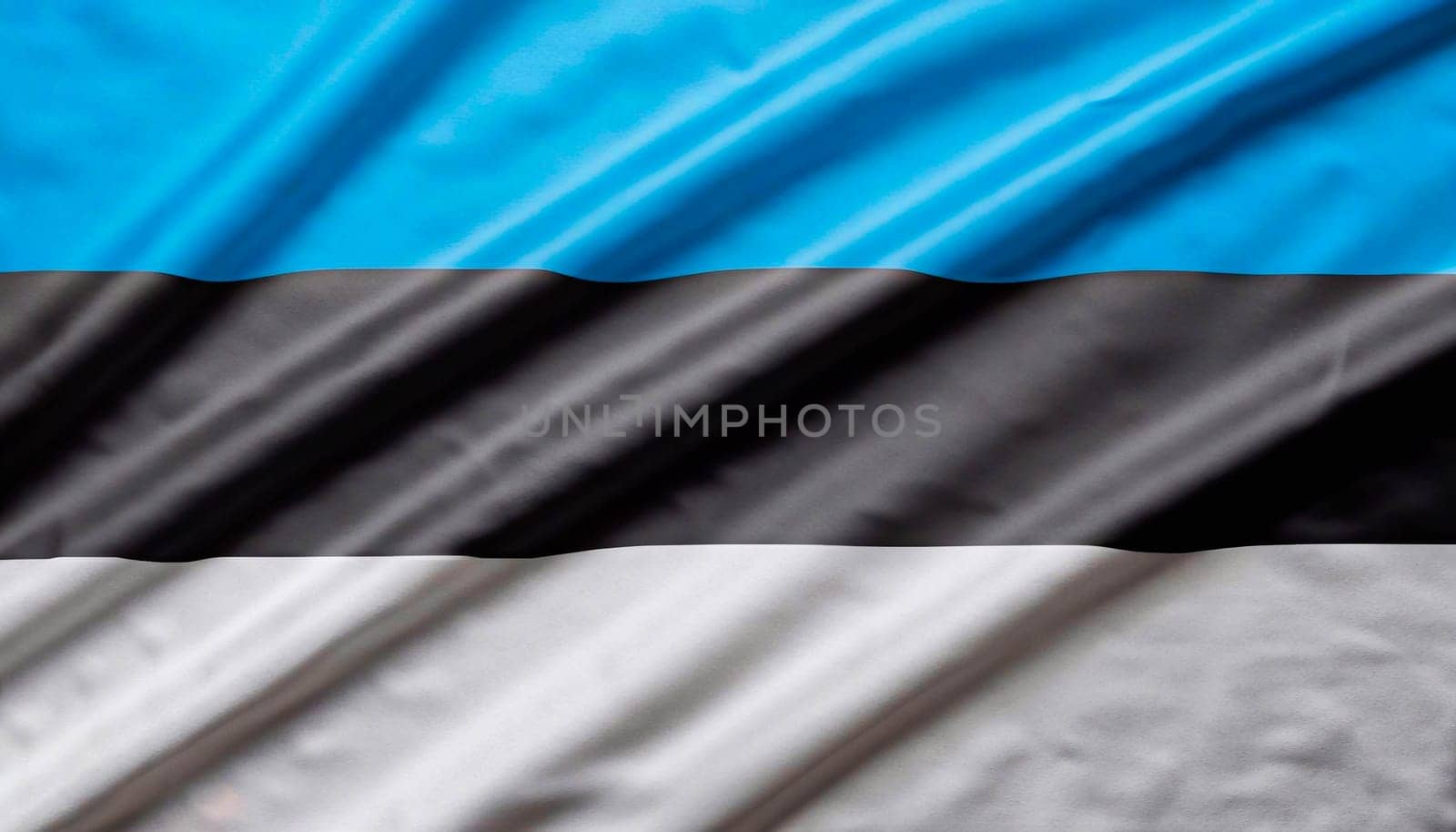 Estonia flag with big folds waving close up under the studio light indoors. The official symbols and colors in fabric banner