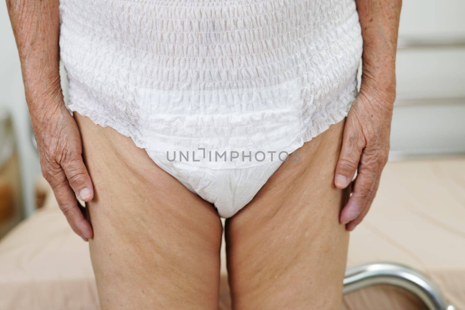 Asian elder senior woman patient wearing adult incontinence diaper pad in hospital.