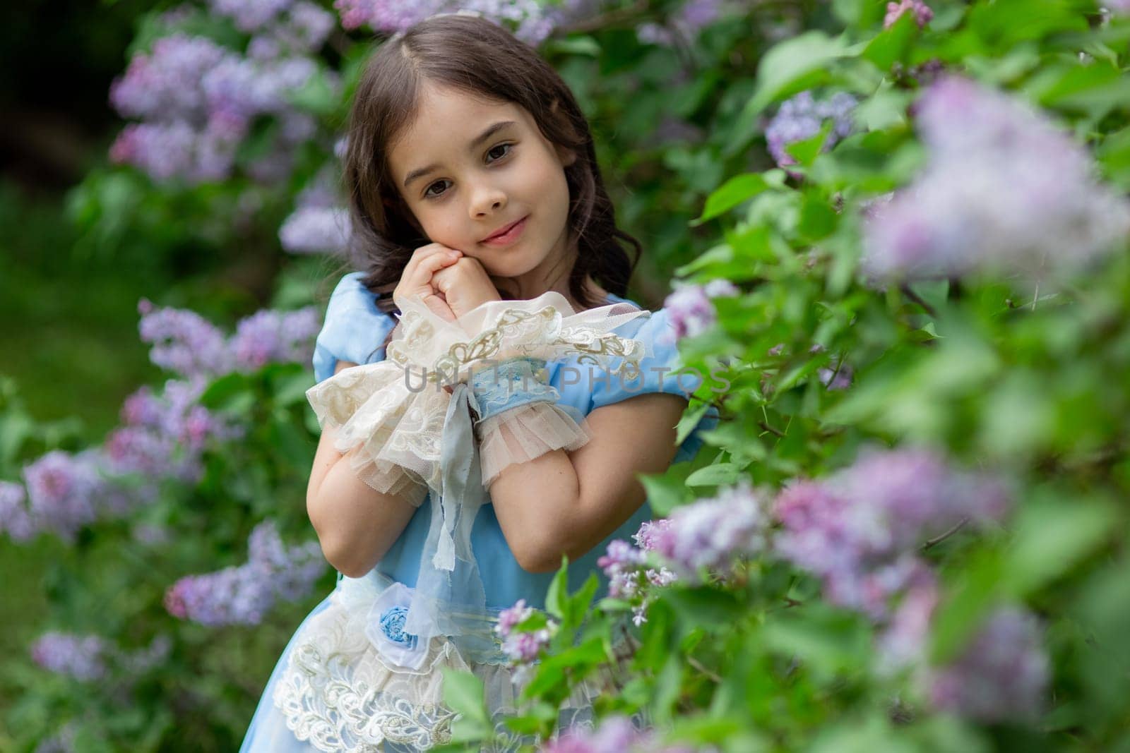 Caucasian young girl in blue dress with flowers in garden.