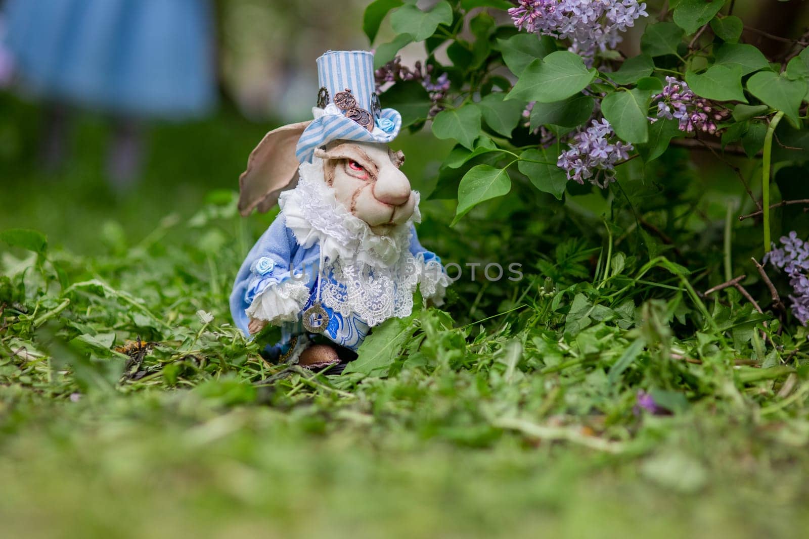 White rabbit in blue victorian outfit among lilac and greenery in a garden scene.