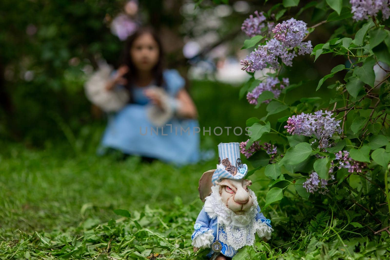 White rabbit figurine in garden with young caucasian girl in background.
