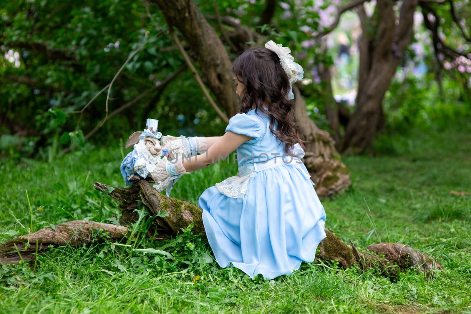 Young brunette girl in blue dress playing with toys in forest.
