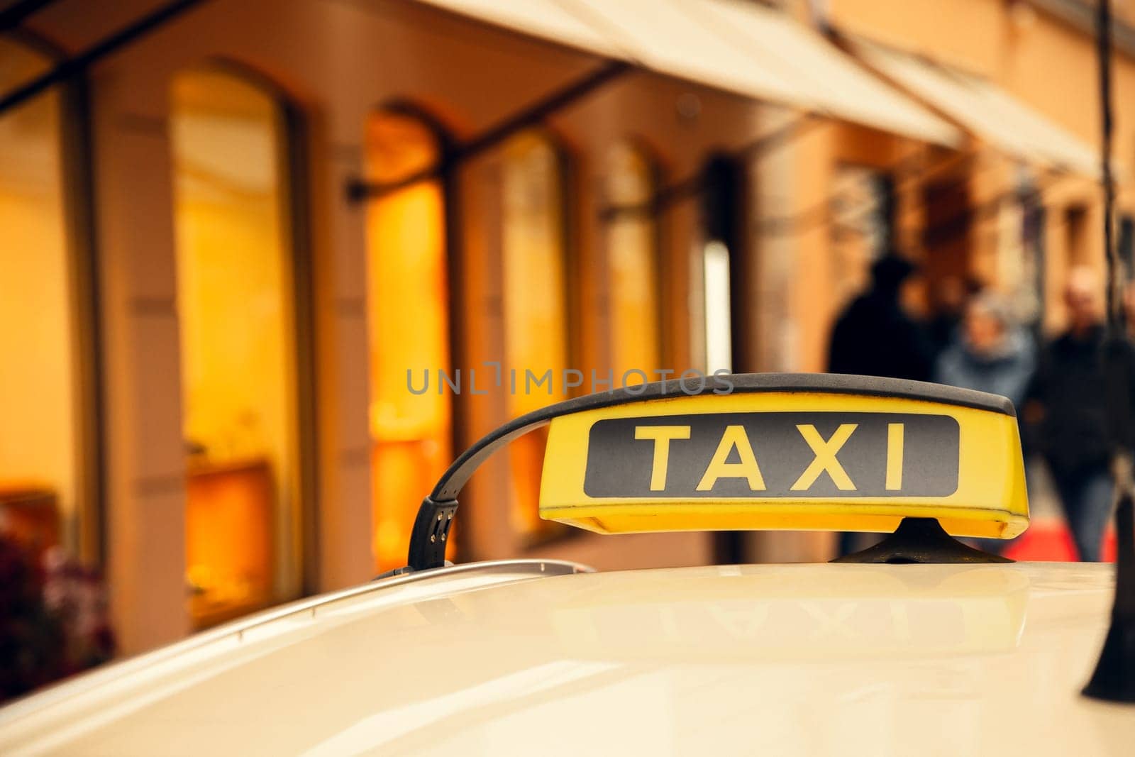 A close-up of a yellow taxi sign on a car roof, glowing against a blurred city background with warm lights. Ideal for transportation, travel, and urban lifestyle themes.