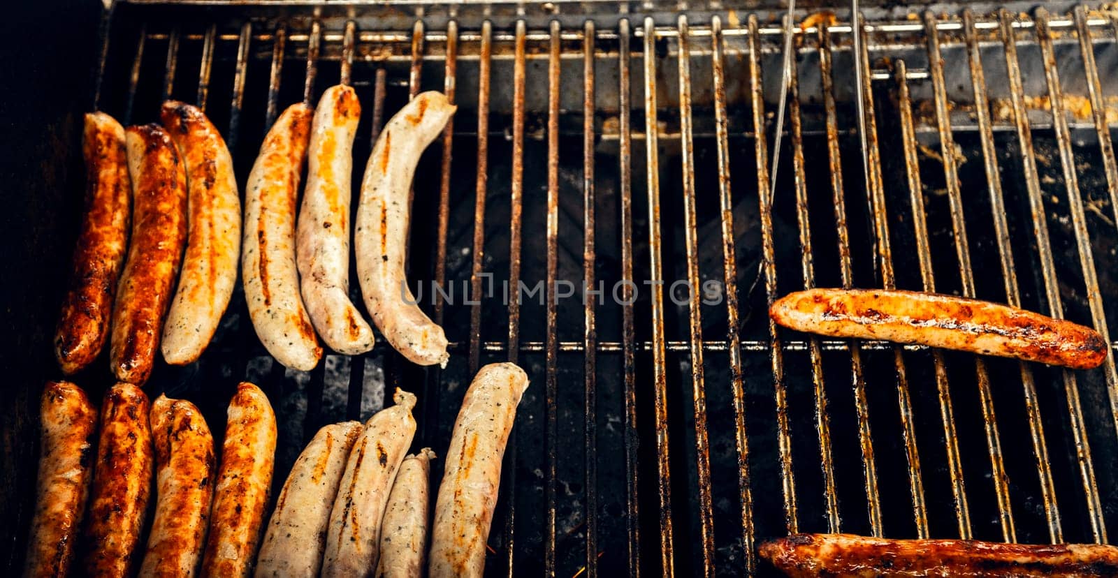 Delicious grilled sausages sizzling on a barbecue with a golden-brown crust. Ideal for food blogs, restaurant menus, barbecue-themed designs, and summer cooking visuals.