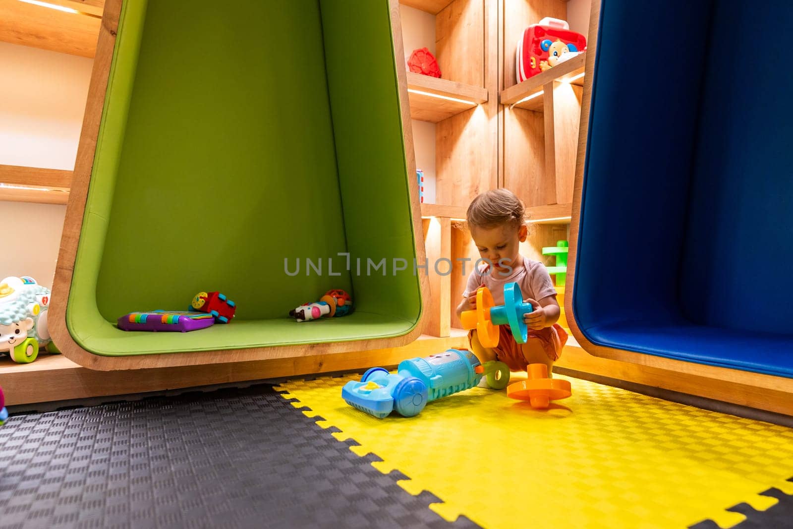 Toddler playing with activity toys and exploring a modern, colorful, and cozy indoor playroom