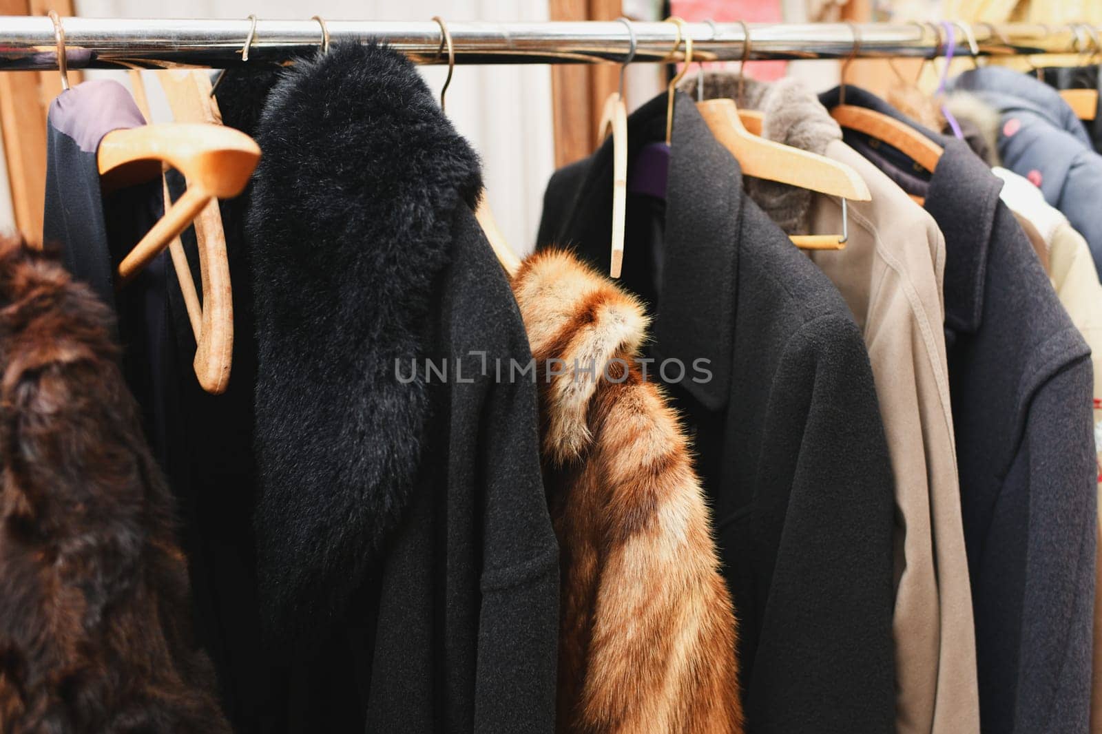 A vintage fur coat, a coat with a fur collar, a coat made of fox or rabbit fur hang on a hanger in a second-hand store.