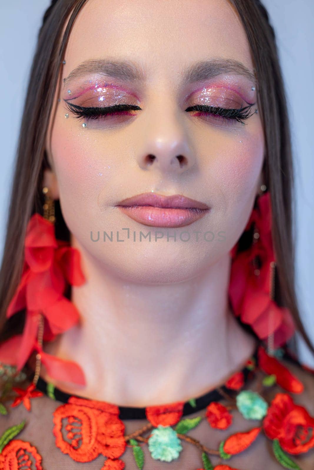 A stunning and captivating portrait of a model showcasing bold glitter makeup and vibrant, fashionable floral attire